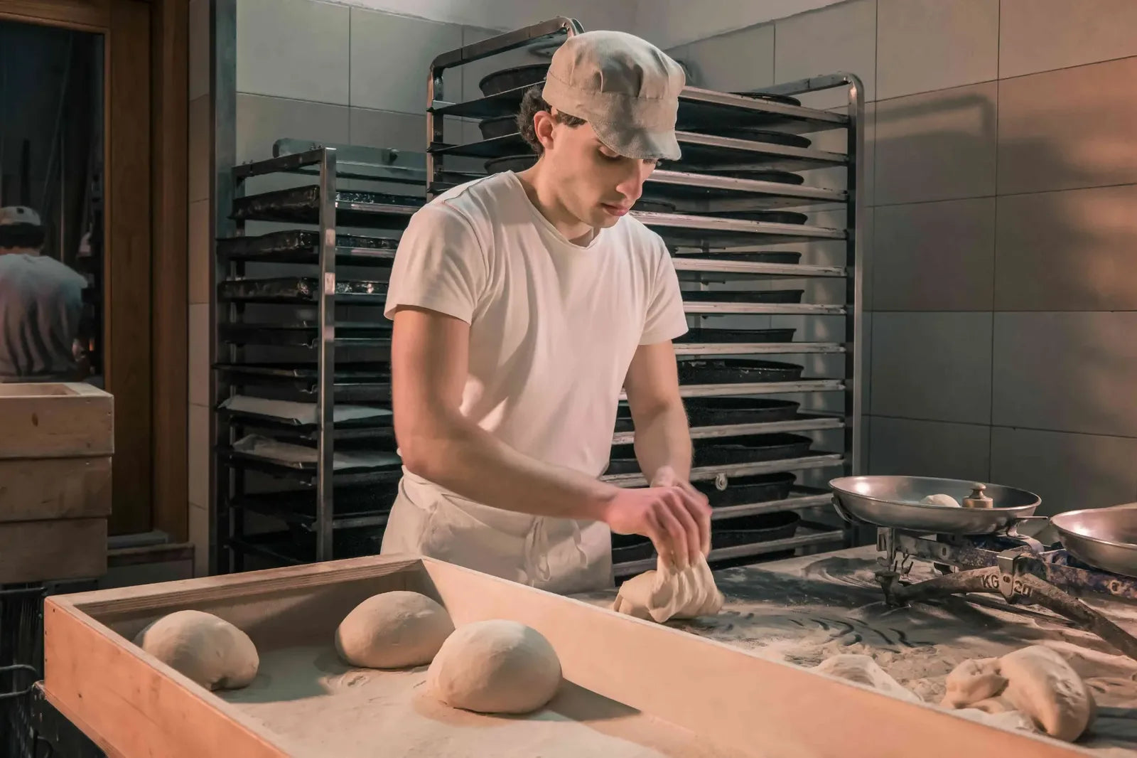 Panetti di impasto artigianale disposti in una cassetta di legno all’interno del laboratorio del panificio.
