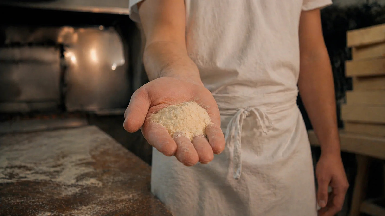Mano di un panettiere che mostra farina di semola all’interno di un forno